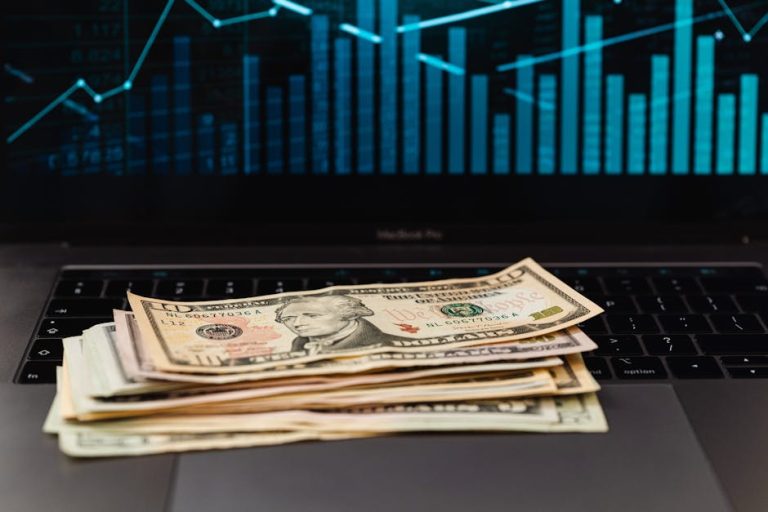 Dollar bills on laptop with financial growth chart representing dividend income